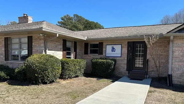 Exterior of a single-story brick building with shrubs, a walkway, and a sign reading “Georgia Advanced Healthcare.”